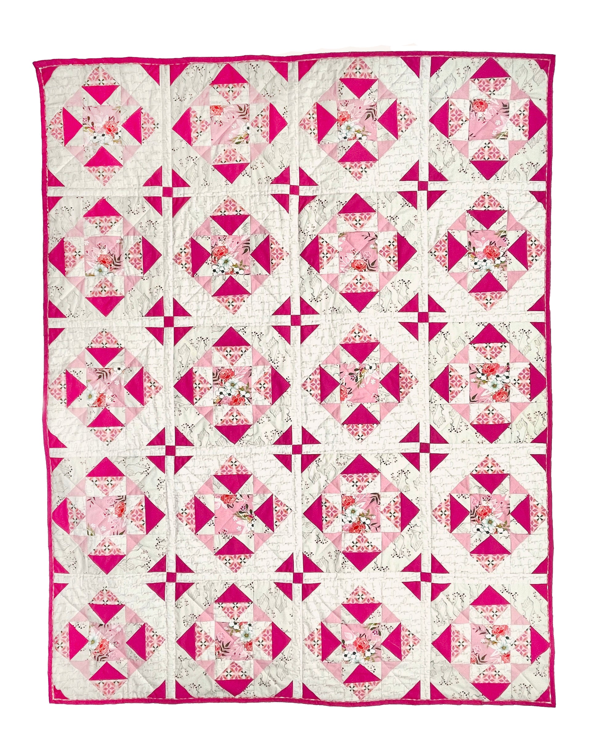 Alta Blooms quilt. A geometric quilt with a small star motif and triangular accents. Bright and medium pinks on a light cream background. Displayed flat on a white surface.
