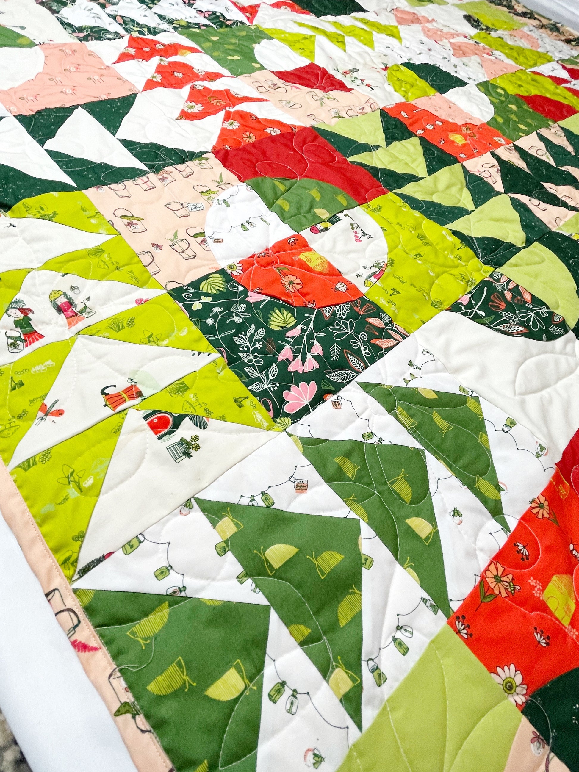 Carrol’s Garden quilt. A geometric quilt with quarter circles distributed with groups of four flying geese. Made of green, red, peach, and white fabrics. Displayed flat and zoomed in on one side.