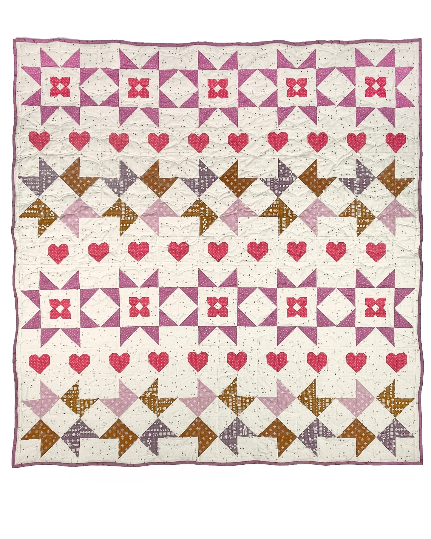 Nyla Star quilt. A star quilt with heart motifs and a flower within some star blocks. Made of pink, purple, and brown fabric on a light background. Displayed flat on a white surface.