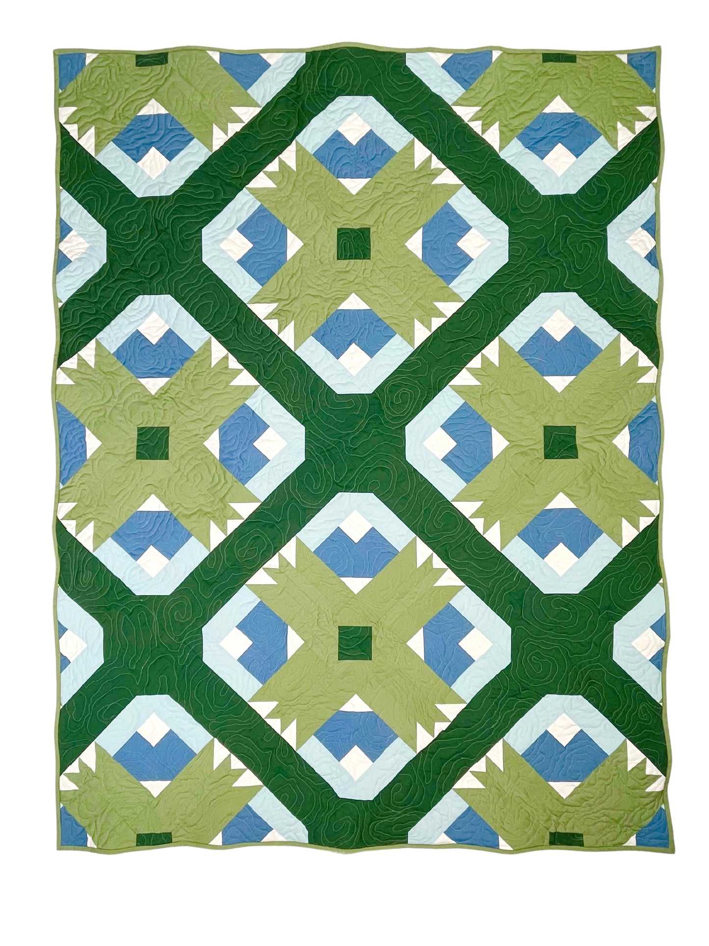 Wasatch quilt. A quilt with a repeating motif that appears similar to a mountain capped with snow above green strips. Blocks set on point. Rotated so blocks appear as a trellis design. Made with green, blue, and white fabric. Displayed flat on a white surface.